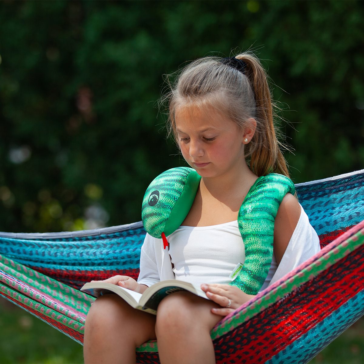 Child wearing a manimo green snake plush wrapped around their shoulders, demonstrating its calming effect in a relaxed setting.