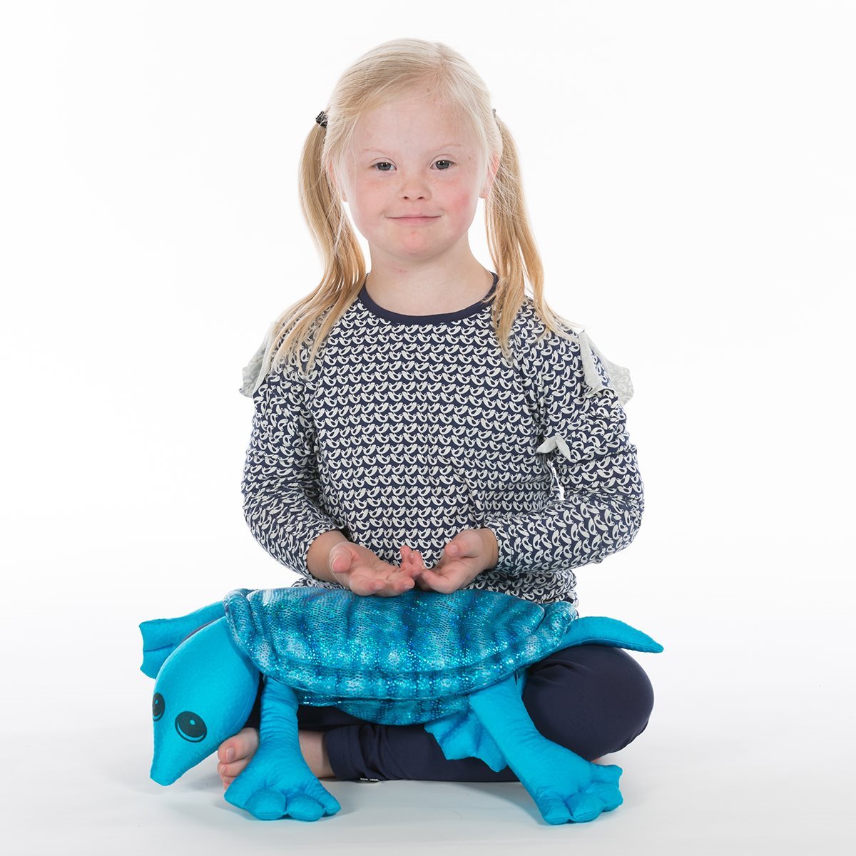 Young girl holding a turquoise weighted turtle plush from manimo, demonstrating its comforting weight and texture.