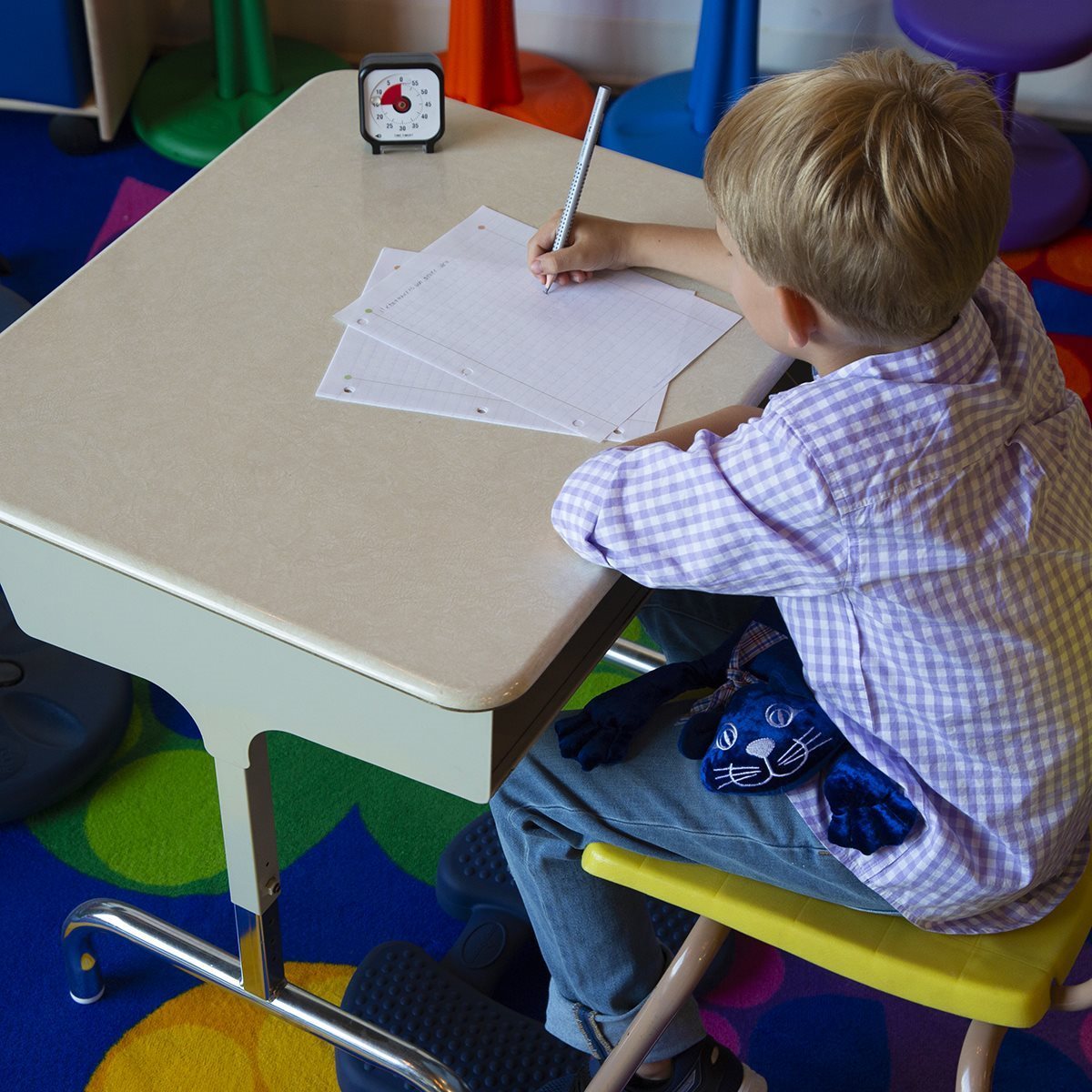 A child holding a 1 kg manimo cat plush in a school setting, demonstrating its comforting presence during activities.