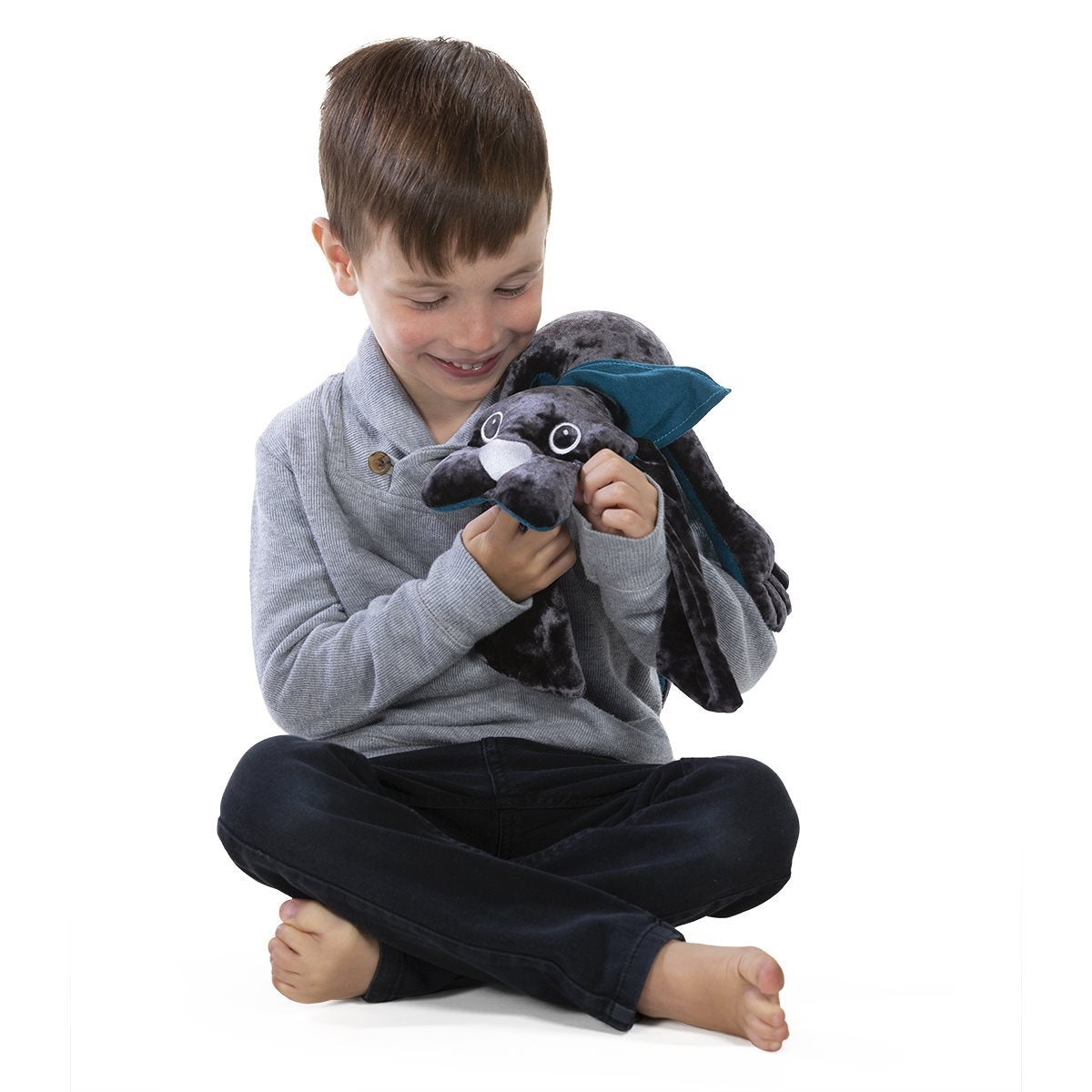 manimo dog plush weighing 1 kg, resting on a child’s lap while sitting, highlighting its use for sensory relaxation.