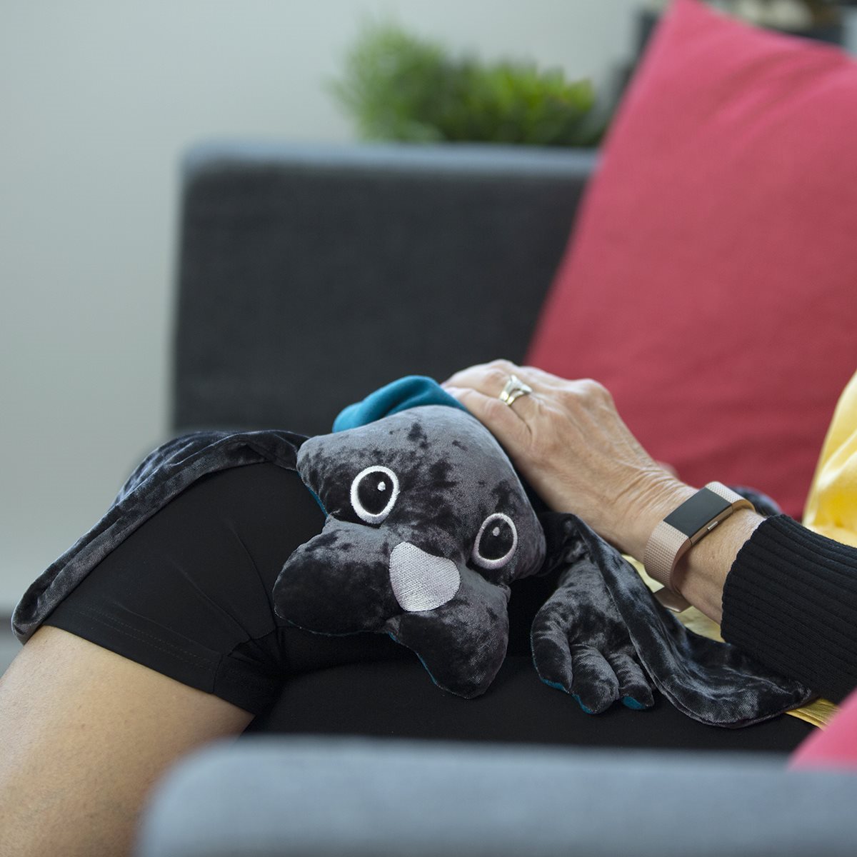 An adult resting with a 2 kg manimo dog plush on their knee, demonstrating its calming effects.