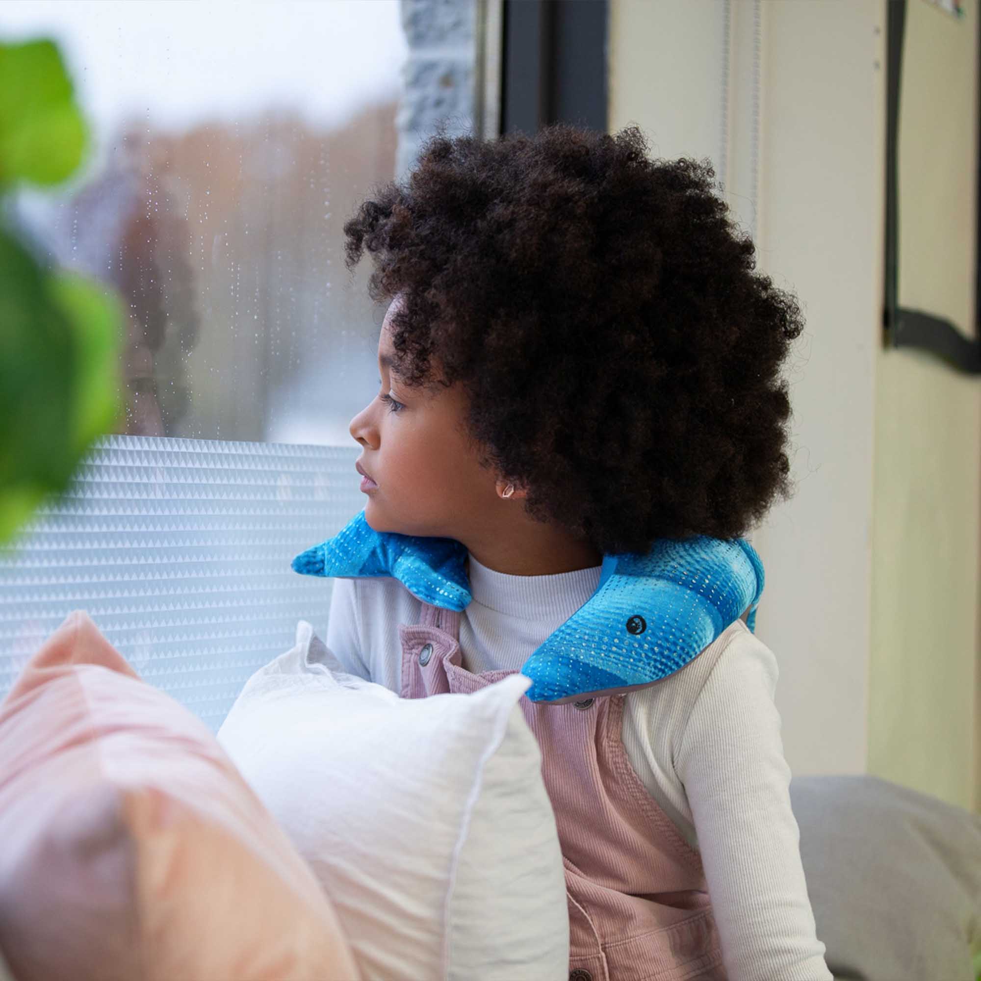 Child interacting with a blue manimo dolphin plush, highlighting its use for sensory relaxation and comfort.